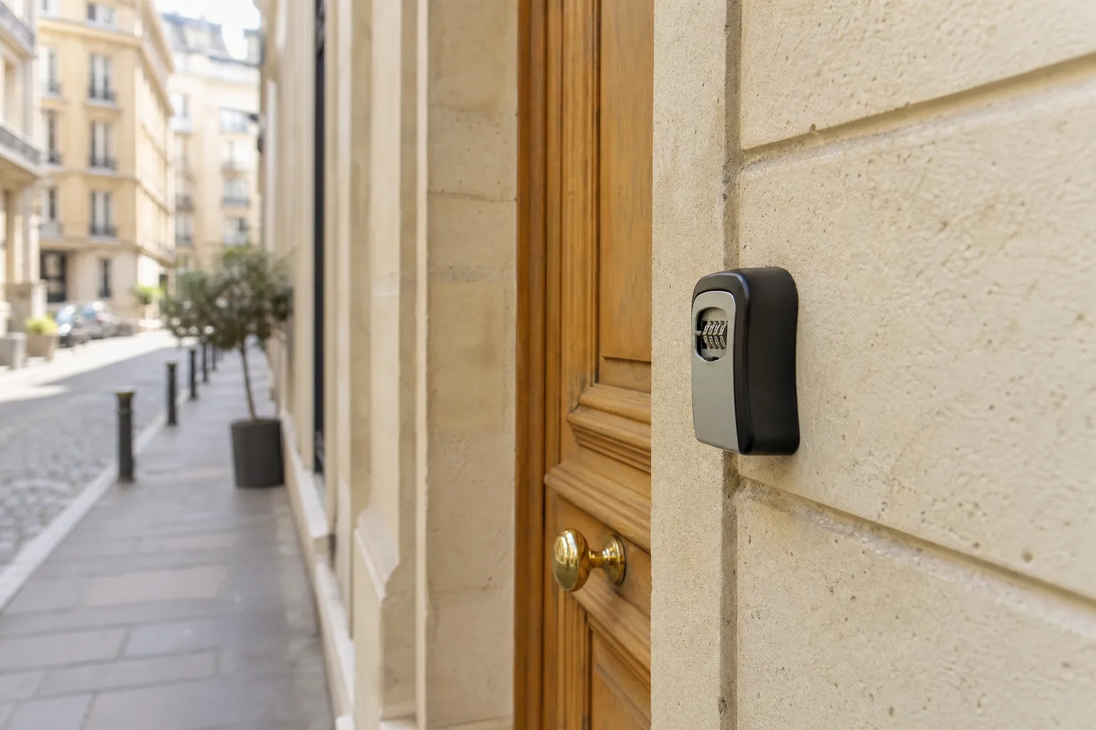 Boîte à clés à code fixée sur le mur de pierre claire d’une entrée d’immeuble ancien